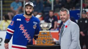 Kitchener Rangers' Sam O'Reilly and OHL commissioner Bryan Crawford pose with the Stafford Smythe Memorial Trophy after O'Reilly was named the tournament MVP after Kitchener defeated the Everett Silvertips to win the Memorial Cup final hockey game, in Kelowna, B.C., on Sunday, May 31, 2026. (Darryl Dyck/THE CANADIAN PRESS)