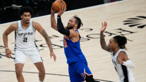 New York Knicks guard Jalen Brunson (11) shoots as San Antonio Spurs guard Dylan Harper (2) and guard Devin Vassell, right, defend during the first half of Game 2 of the NBA Finals basketball series, Friday, June 5, 2026, in San Antonio. (David J. Phillip/AP)