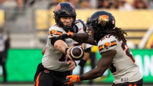 B.C. Lions quarterback Nathan Rourke (12) hands the ball to B.C. Lions' James Butler (20) during first half CFL football action against the Hamilton Tiger-Cats in Hamilton on Thursday, August 7, 2025. (Nick Iwanyshyn/THE CANADIAN PRESS)