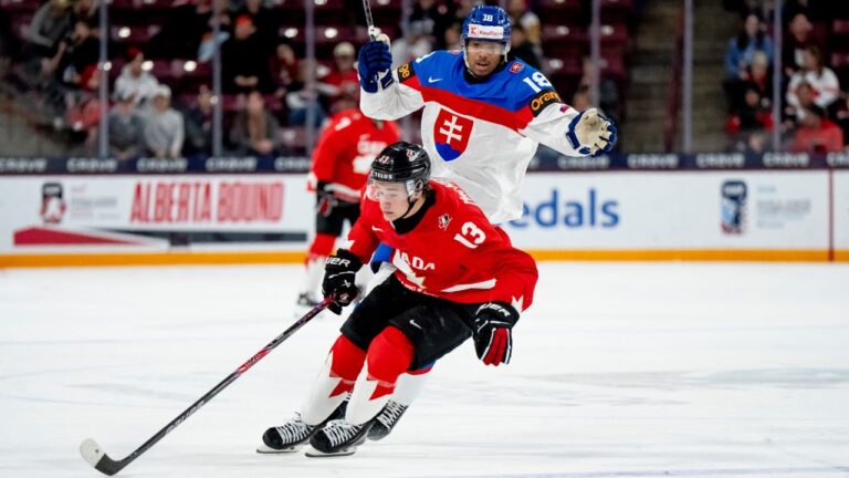 Canada's Ethan MacKenzie (13) takes the puck from Slovakia's Samuel Murin (18) during third period IIHF World Junior Championship quarterfinal hockey action, in Minneapolis, Minn., on Friday, January 2, 2026. (Christopher Katsarov/THE CANADIAN PRESS)