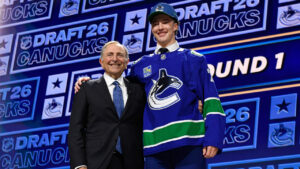 Caleb Malhotra, right, stands with NHL Commissioner Gary Bettman, left, after being drafted by the Vancouver Canucks during the NHL hockey draft Friday, June 26, 2026, in Buffalo, N.Y. (Adrian Kraus/AP)