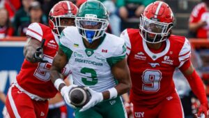 Saskatchewan Roughriders' Keesean Johnson, centre, makes a touchdown catch as Calgary Stampeders' Kelechi Anyalebechi, left, and Damon Webb chase him during second half CFL football action in Calgary, Saturday, June 20, 2026. (Jeff McIntosh/THE CANADIAN PRESS)
