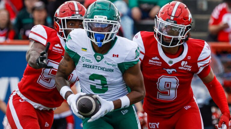 Saskatchewan Roughriders' Keesean Johnson, centre, makes a touchdown catch as Calgary Stampeders' Kelechi Anyalebechi, left, and Damon Webb chase him during second half CFL football action in Calgary, Saturday, June 20, 2026. (Jeff McIntosh/THE CANADIAN PRESS)
