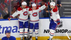 Montréal Canadiens right wing Cole Caufield (13), centre, celebrates his goal with centre Nick Suzuki (14), left, and defenseman Kaiden Guhle (21), right, during the third period of an NHL hockey game against the Buffalo Sabres Saturday, Jan. 31, 2026, in Buffalo, N.Y. (Jeffrey T. Barnes/AP)
