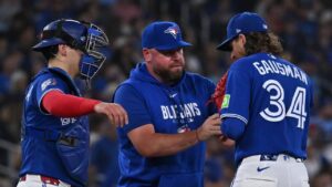 Toronto Blue Jays pitcher Kevin Gausman (34) is taken out of the game against the Tampa Bay Rays by manager John Schneider, centre, during the fourth inning of their MLB baseball game in Toronto on Tuesday, July 21, 2026. (Jon Blacker/CP)