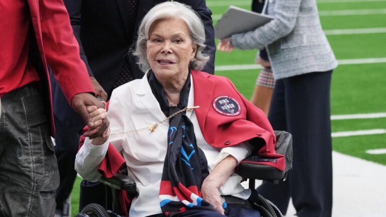 Janice McNair, co-founder and senior chair of the Houston Texans, center, is escorted by former Houston Texans player Andre Johnson, right, following a ceremony where McNair was celebrated as a new member of the team's ring of honor at half time of an NFL football game against the Denver Broncos Sunday, Nov. 2, 2025, in Houston. (AP Photo/Eric Gay)