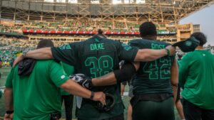 Members of the Saskatchewan Roughriders react to a memorial video tribute to Roughrider linebacker Jayden Dalke, and Bhishma Rajyaguru, who were killed in a highway crash, prior to first half CFL football action against the Edmonton Elks in Regina on Thursday, July 23, 2026. (Kayle Neis/CP)