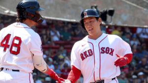 Boston Red Sox designated hitter Masataka Yoshida, right, high fives teammate Anthony Seigler (48) after scoring during the second inning of the first baseball game of a doubleheader against the Tampa Bay Rays, Friday, July 17, 2026, in Boston. (AP Photo/Mark Stockwell)