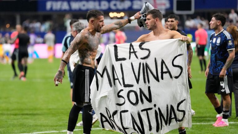 Argentina's Giovani Lo Celso holds a banner with the words "The Malvinas are Argentine", referring to the Falkland Islands, while teammate Nicolas Otamendi gestures to him, at the end of the World Cup semifinal match between England and Argentina in Atlanta, on Wednesday, July 15, 2026. (Rebecca Blackwell/AP)