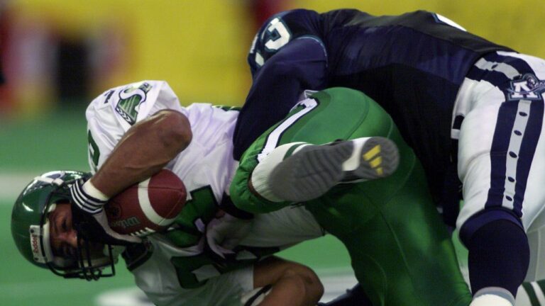 Saskatchewan Roughriders' Eric Guliford (left) is flipped and hammered to the turf by Toronto Argonauts' Calvin Tiggle during a CFL game in Toronto. (Frank Gunn/CP)