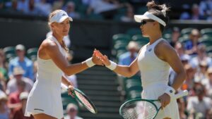 Kristina Mladenovic of France, left taps hands with playing partner Hanyo Guo of China during the women's doubles final, playing against Luisa Stefani of Brazil and Gabriela Dabrowski of Canada, at Wimbledon Tennis Championships in London, Sunday, July 12, 2026. (AP Photo/Kin Cheung)