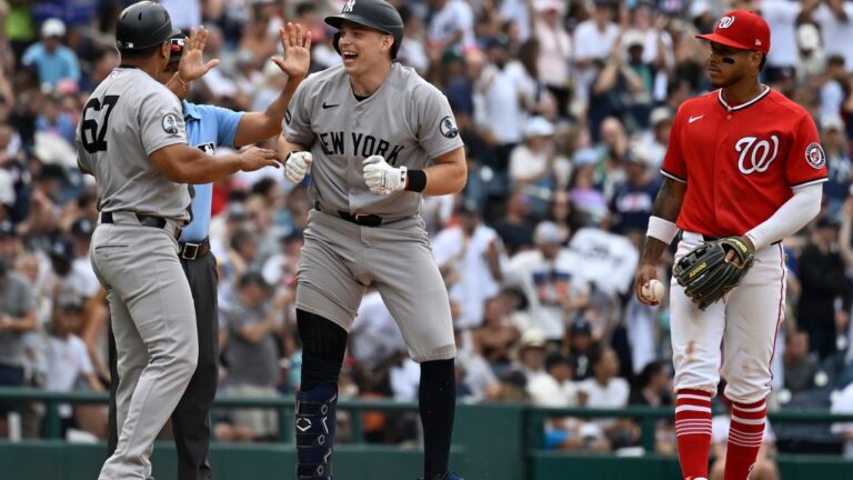New York Yankees' Ben Rice, center, celebrates with third base coach Luis Rojas, left, after hitting a two-RBI triple as Washington Nationals third baseman Jorbit Vivas, right, looks on during the eighth inning of a baseball game, Sunday July 12, 2026, in Washington. (AP Photo/John McDonnell)