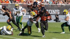 B.C. Lions' James Butler (20) runs past Edmonton Elks' Richard Jibunor (96) during first half CFL football action in Kelowna, B.C., on Saturday July 4, 2026. (Steve Dunsmoor/CP)