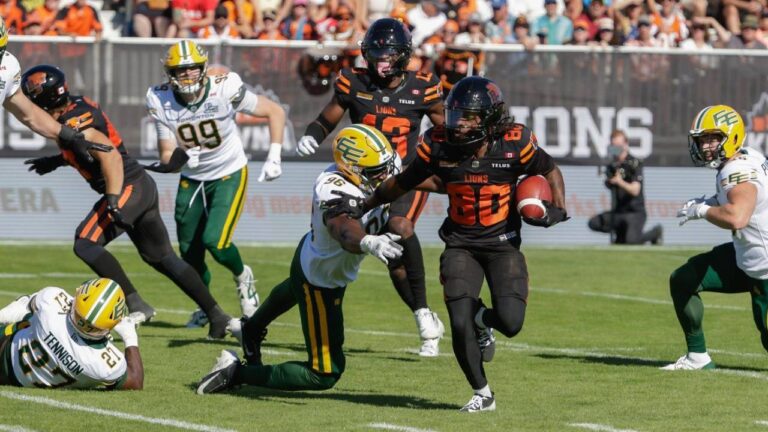 B.C. Lions' James Butler (20) runs past Edmonton Elks' Richard Jibunor (96) during first half CFL football action in Kelowna, B.C., on Saturday July 4, 2026. (Steve Dunsmoor/CP)