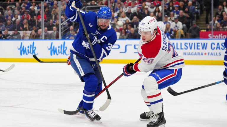 Montréal Canadiens left wing Juraj Slafkovský (20) and Toronto Maple Leafs centre Auston Matthews (34) fight for control of the puck during first period NHL hockey action in Toronto on Saturday, Dec. 6, 2025. (Frank Gunn/CP)