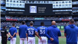 Players and coaches of the Toronto Blue Jays recognize a moment of silence on the announcement of the passing of former Blue Jays pitcher Duane Ward prior to the start of the game against the Chicago White Sox in MLB baseball action in Toronto on Sunday, July 19, 2026. (Jon Blacker/THE CANADIAN PRESS)