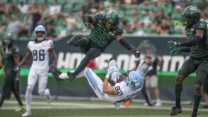 Toronto Argonauts' Tyler Kahmann (82) catches a touchdown pass as Saskatchewan Roughriders' Nelson Lokombo (25) defends during first half CFL football action in Regina on Saturday, Aug. 29, 2026. (Kayle Neis/CP)