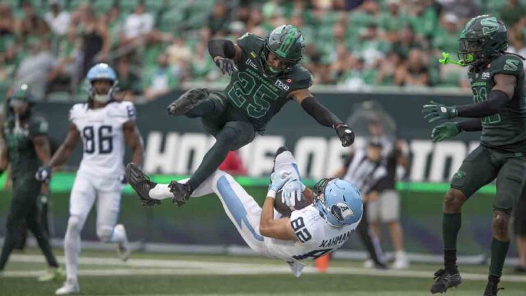 Toronto Argonauts' Tyler Kahmann (82) catches a touchdown pass as Saskatchewan Roughriders' Nelson Lokombo (25) defends during first half CFL football action in Regina on Saturday, Aug. 29, 2026. (Kayle Neis/CP)