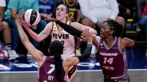 Indiana Fever guard Caitlin Clark (22) shoots over Toronto Tempo forward Teonni Key (7) and center Temi Fagbenle (14) in the first half of a WNBA Commissioner's Cup basketball game in Indianapolis, Tuesday, June 16, 2026. (AP Photo/Michael Conroy)
