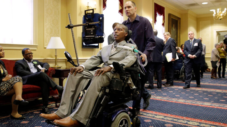Former Baltimore Ravens NFL football player O.J. Brigance, centre, current senior advisor to player development, is pushed by a nurse outside of a committee room in Annapolis, Md., March 10, 2015, after testifying to Maryland lawmakers against a right-to-die bill. (Patrick Semansky/AP)