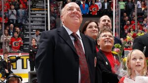 Former Calgary Flames broadcaster Peter Maher and his family watch a video honouring his career during a pre game ceremony against the Anaheim Ducks at Scotiabank Saddledome on November 18, 2014 in Calgary, Alberta, Canada. (Photo by Gerry Thomas/NHLI via Getty Images)