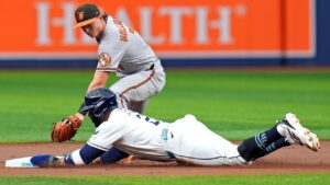 Tampa Bay Rays' Yandy Diaz slides into second base ahead of the tag by Baltimore Orioles second baseman Jackson Holliday (7) after tagging up a on a fly out by Jonathan Aranda during the first inning of a baseball game Monday, Aug. 17, 2026, in St. Petersburg, Fla. (Chris O'Meara/AP)