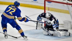 Winnipeg Jets goalie Connor Hellebuyck, right, stops a shot by Buffalo Sabres right winger Tage Thompson during overtime in an NHL game in Buffalo, N.Y., Wednesday, March 30, 2022. (Adrian Kraus/AP)