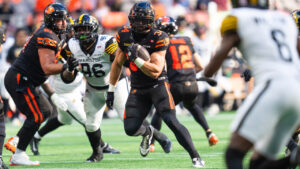 B.C. Lions' Zander Horvath (centre) runs past Hamilton Tiger-Cats Charbel Dabire (second left) during second half of CFL football action in Vancouver on Saturday, August 8, 2026. (Rich Lam/CP)