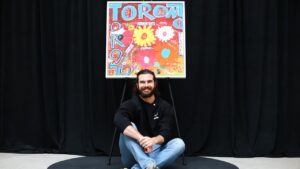 Toronto Blue Jays pitcher Dylan Cease sits under his painting during an event at the Art Gallery of Ontario in Toronto, Tuesday, August 25, 2026. (Cole Burston/CP)