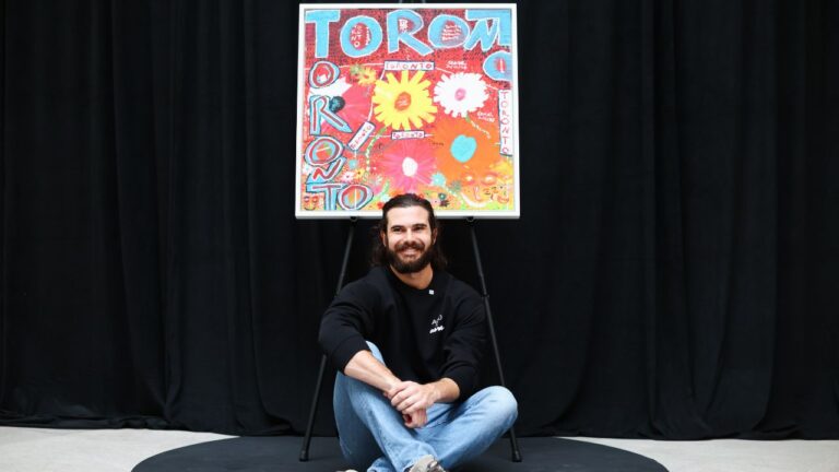 Toronto Blue Jays pitcher Dylan Cease sits under his painting during an event at the Art Gallery of Ontario in Toronto, Tuesday, August 25, 2026. (Cole Burston/CP)