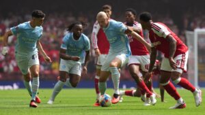 Manchester City's Erling Haaland, centre, and Arsenal's Myles Lewis-Skelly challenge for the ball during the FA Community Shield final soccer match between Arsenal and Manchester City in Cardiff, Wales, Sunday, Aug.16, 2026. (Alastair Grant/AP)