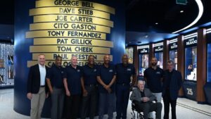 Former Toronto Blue Jays players and management, from left, Mark Shapiro, George Bell, Dave Stieb, Joe Carter, Cito Gaston, Carlos Delgado, Pat Gillick (seated), Jose Bautista and Paul Beeston open the team's new Hall of Excellence at Rogers Centre in Toronto on Saturday, Aug. 29, 2026. (Jon Blacker/CP)