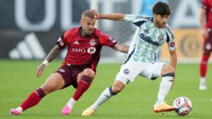 Toronto FC midfield Niklas Dorsch (6) chases New England Revolution midfield Carles Gil (10) during first half MLS soccer action in Toronto, Saturday, Aug. 15, 2026. (Nathan Denette/CP)