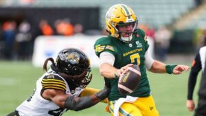 Edmonton Elks quarterback Cody Fajardo (7) runs with the ball under pressure from Hamilton Tiger-Cats' Wynton McManis (48) during first half CFL football action in Edmonton on Saturday, Sept. 26, 2026. (Codie McLachlan/CP)