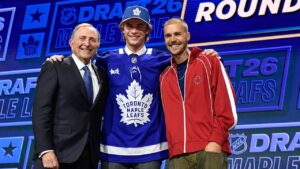 Gavin McKenna, center, stands with NHL Commissioner Gary Bettman, left, and singer Justin Bieber, right, after being drafted by the Toronto Maple Leafs during the NHL hockey draft Friday, June 26, 2026, in Buffalo, N.Y. (AP Photo/Adrian Kraus)