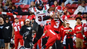 Ottawa Redblacks' Kyahva Tezino, top left, chases Calgary Stampeders quarterback Vernon Adams Jr. during second half CFL football action in Calgary, Saturday, Sept. 19, 2026. (Jeff McIntosh/CP)