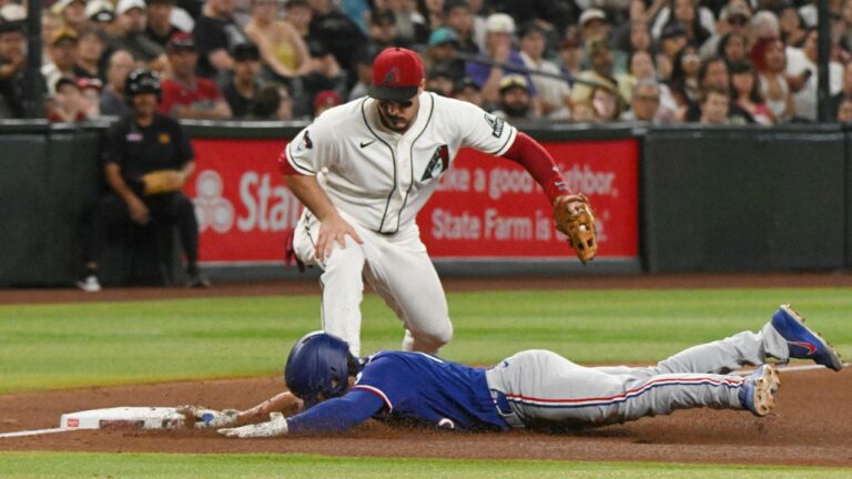Texas Rangers' Justin Foscue, bottom, slides safely into third as Arizona Diamondbacks' Nolan Arenado, top, watches in the fourth inning of a baseball game, Sunday, Sept. 13, 2026, in Phoenix. (Caitlin O'Hara/AP Photo)