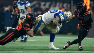 B.C. Lions' Parker McKenna (42) and Robert Carter Jr. (0) stop Winnipeg Blue Bombers' Brady Oliveira (20) during the first half of a CFL football game, in Vancouver, on Friday, Oct. 23, 2026. (Ethan Cairns/CP)