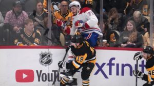 Pittsburgh Penguins' Connor Dewar (19) checks Montreal Canadiens' Jake Evans (71) into the boards during the first period of an NHL hockey game in Pittsburgh, Saturday, Oct. 3, 2026. (AP Photo/Gene J. Puskar)