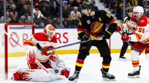 Calgary Flames goalie Devin Cooley (1) stops the puck as Vancouver Canucks' Linus Karlsson (94) and Flames' Jacob Middleton (55) battle in front of the net during the third period of an NHL hockey game, in Vancouver, on Saturday, Oct. 3, 2026. (Jacob Mallari/CP)