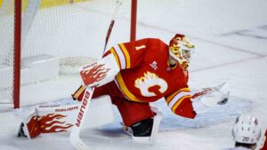 Carolina Hurricanes' Sebastian Aho, right, looks on as Calgary Flames goalie Devin Cooley grabs his shot during second period NHL hockey action in Calgary on Sunday, Oct. 18, 2026. (Jeff McIntosh/CP)
