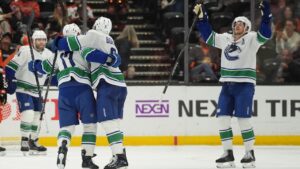 Teammates celebrate with Vancouver Canucks defenceman Filip Hronek (17) after his goal during overtime in an NHL hockey game against the Anaheim Ducks Tuesday, Oct. 27, 2026, in Anaheim, Calif. (AP Photo/Gregory Bull)