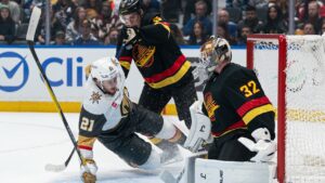 Vancouver Canucks’ Tom Willander (5) knocks down Las Vegas Golden Knights’ Brett Howden (21) as he crashes the net of goalie Kevin Lankinen (32) during first period NHL hockey action in Vancouver, Sunday, Oct. 4, 2026. (Rich Lam/CP)