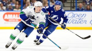 Vancouver Canucks defenseman Zeev Buium (8) moves the puck in front of Tampa Bay Lightning right wing Pontus Holmberg (29) during the first period of an NHL hockey game Saturday, Oct. 17, 2026, in Tampa, Fla. (AP Photo/Chris O'Meara)