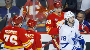 Toronto Maple Leafs' Zack MacEwen, right, skates away as Calgary Flames' Matvei Gridin, centre, celebrates his goal during first period NHL hockey action in Calgary on Monday, Oct. 26, 2026. THE CANADIAN PRESS/Jeff McIntosh