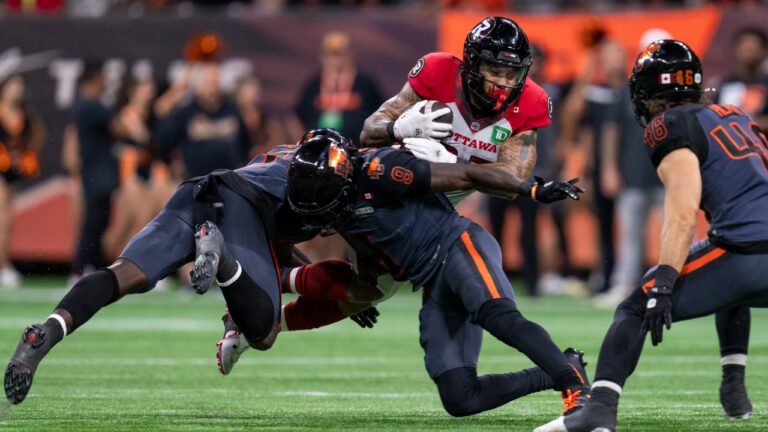 Ottawa Redblacks running back Daniel Adeboboye (25) runs the ball while being tackled by B.C. Lions defensive back Deontai Williams (9) during the second half of a CFL football game in Vancouver, on Friday, September 12, 2025. (Jimmy Jeong/CP)