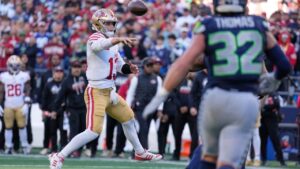 San Francisco 49ers quarterback Brock Purdy (13) throws a pass as Seattle Seahawks linebacker Drake Thomas (32) looks on during the second half of an NFL football game Sunday, Oct. 11, 2026, in Seattle. (AP Photo/Stephen Brashear)