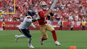 San Francisco 49ers quarterback Brock Purdy, right, runs against Denver Broncos linebacker Nik Bonitto during the second half of an NFL football game in Santa Clara, Calif., Sunday, Oct. 4, 2026. (AP Photo/Kelley L. Cox)
