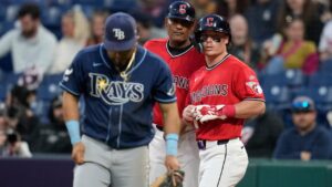 Cleveland Guardians' Travis Bazzana, right, talks with first base and catching coach Sandy Alomar Jr., center, behind Tampa Bay Rays first baseman Jonathan Aranda, left, after a walk in the eighth inning of a baseball game in Cleveland, Tuesday, April 28, 2026. (AP Photo/Sue Ogrocki)