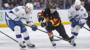Tampa Bay Lightning's J.J. Moser, left, lifts Vancouver Canucks' Elias Pettersson's stick as they vie for the puck during the third period of an NHL hockey game, in Vancouver, on Thursday, March 19, 2026. (Darryl Dyck/CP)
